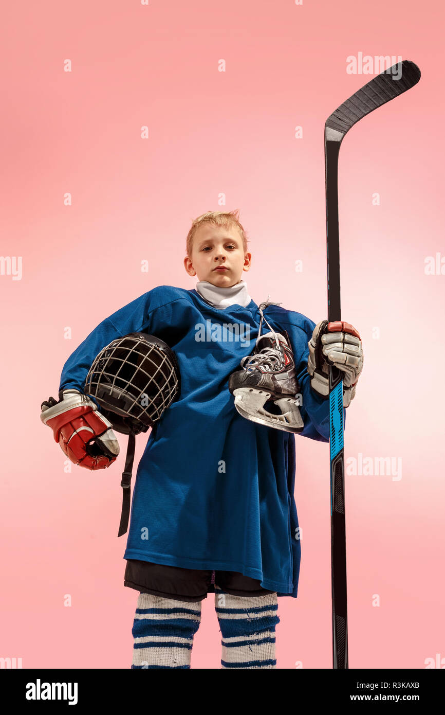 A hockey player in uniform with equipment over pink studio background