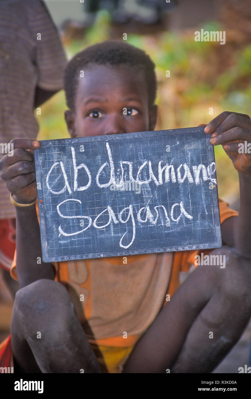 Africa, Mail, Dogon country. Boy from the Dogon tribe holds a tablet where he wrote his name on a chalkboard. Stock Photo