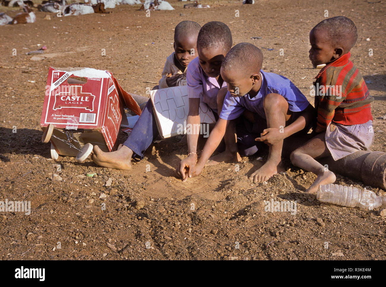 Africa, Namibia. In a group of kids, one teaches another how to write in the dirt. Stock Photo