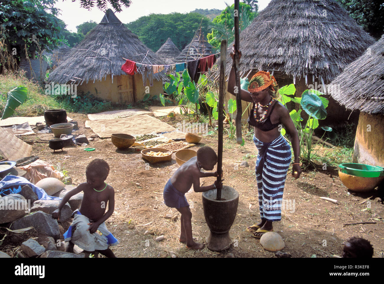 Senegal, Bedik tribe, Iwol village. Amer Keita pounding grain with her three children. Keita is one of the two important families in village of Iwol. Stock Photo
