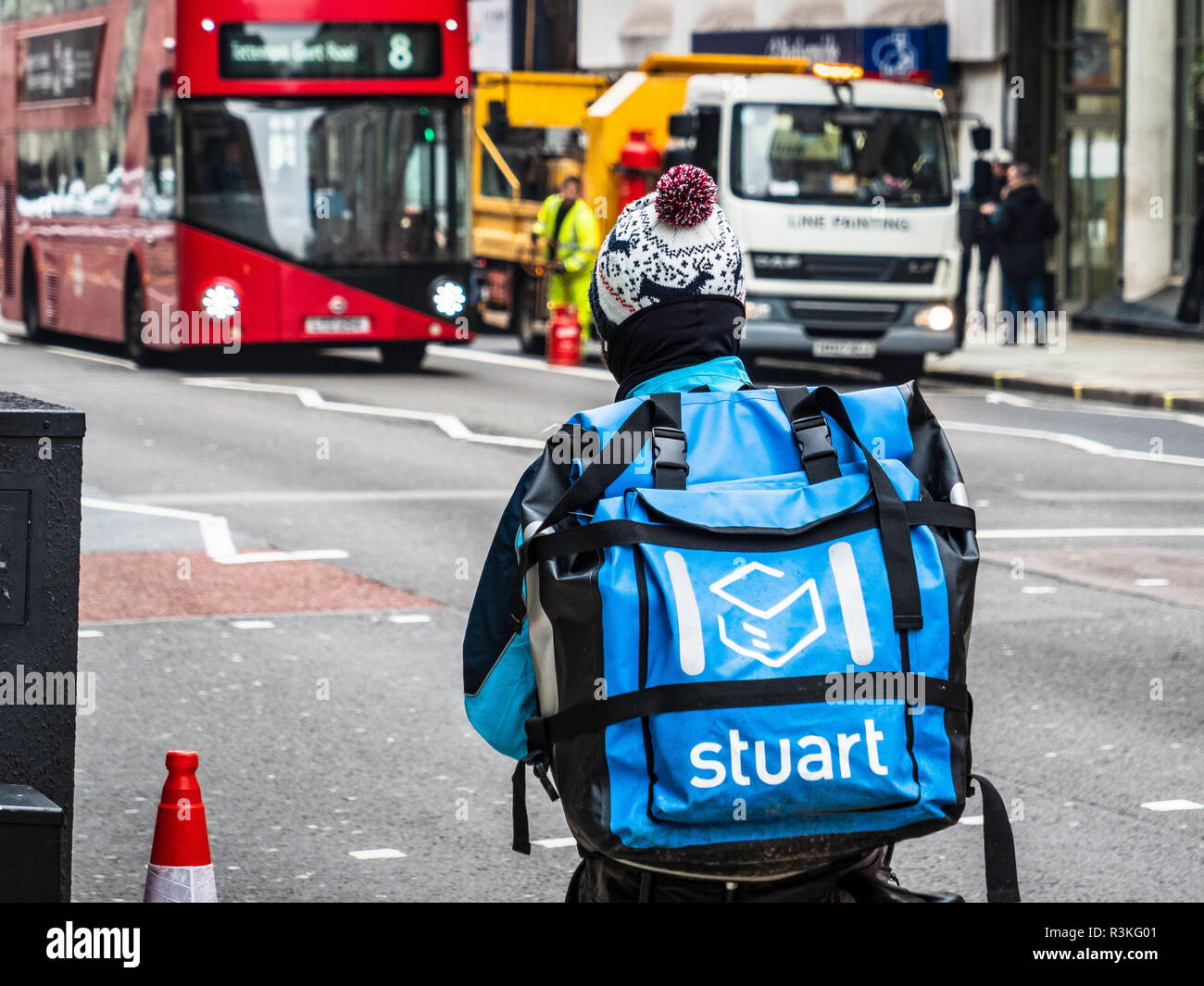A Stuart company food delivery courier rides through London Streets, Stuart is competing with Deliveroo and Uber Eats in this competitive market Stock Photo