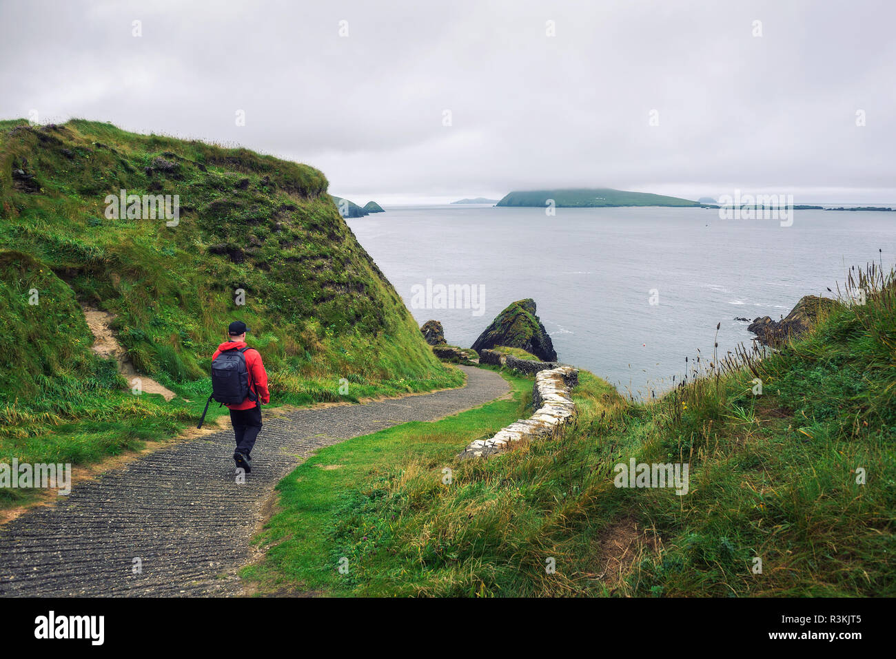 Young man walks along pathway surrounded by irish landscape Stock Photo