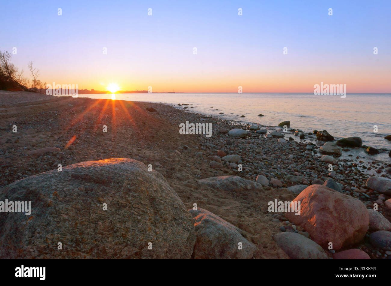 huge stone boulder on the sea, sunset on the rocky seashore Stock Photo