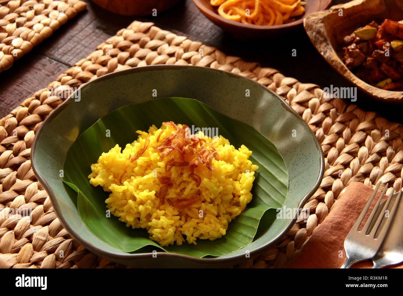 Nasi Kuning. Traditional Indonesian yellow (turmeric) rice, accompanied with several side dishes. Stock Photo