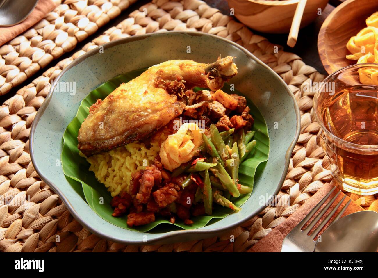 Nasi Kuning. Traditional Indonesian yellow (turmeric) rice, accompanied with several side dishes. Stock Photo