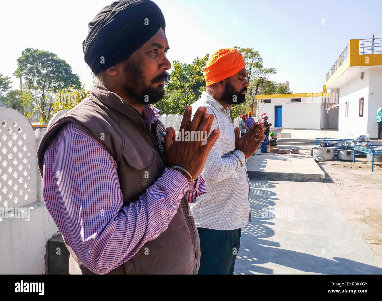 Sikh devotees are seen praying outside Gurdwara or a Sikh temple during the occasion of the 550th birth anniversary of Guru Nanak Dev in Mohali. Sikhism was founded in the 15th century by Guru Nanak, who broke away from Hinduism, India’s dominant religion, He preached the equality of races and genders and the rejection of image-worship and the caste system. Stock Photo