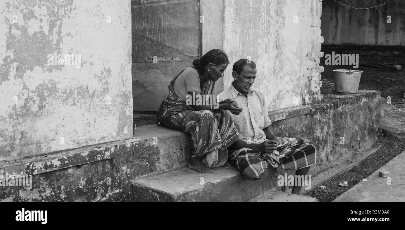 Black and white shot couple of senior people siting on the house exterior Stock Photo