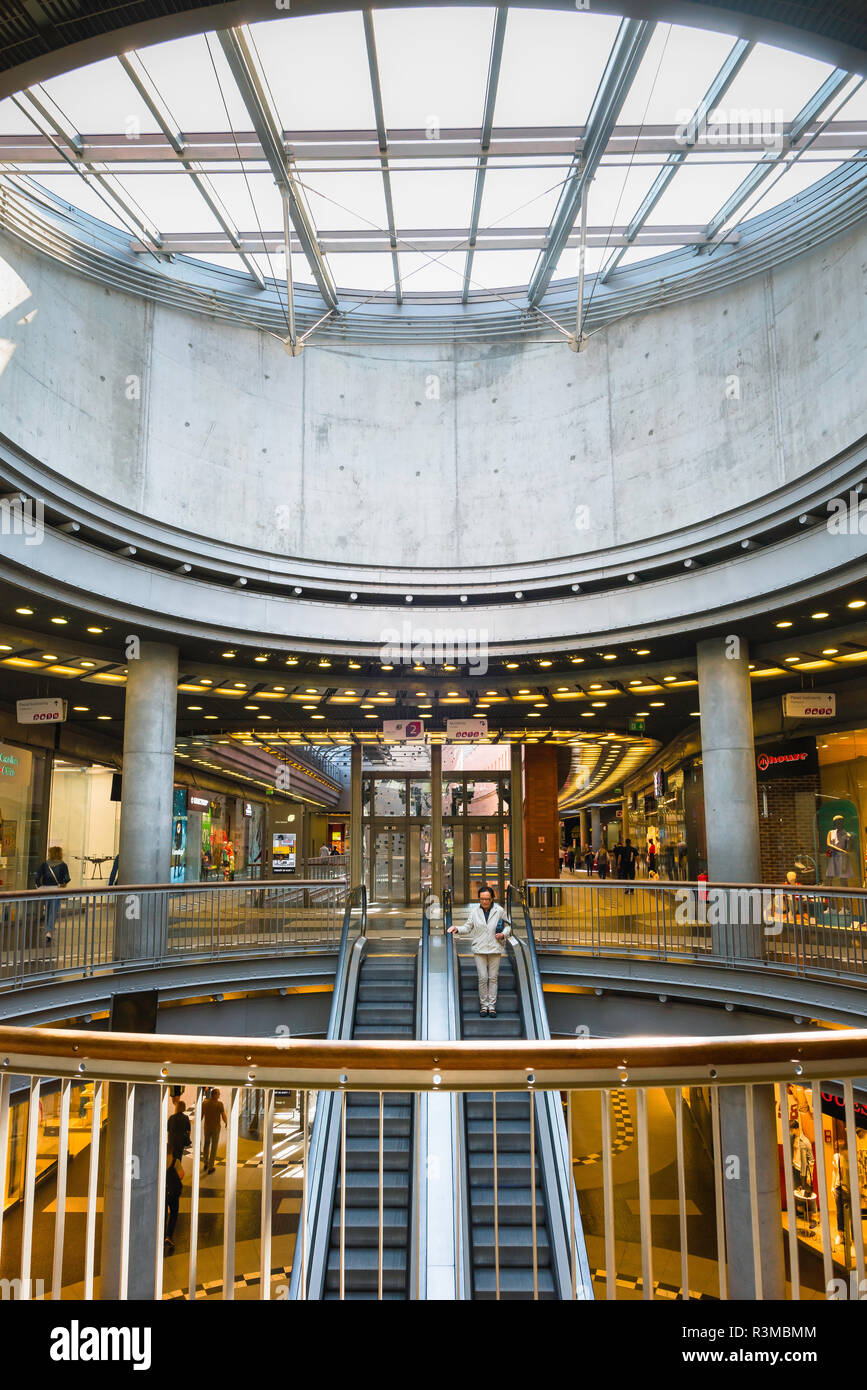 Poznan shopping centre center, view of people using the escalator underneath the grand cupola inside the Stary Browar shopping mall in Poznan, Poland. Stock Photo