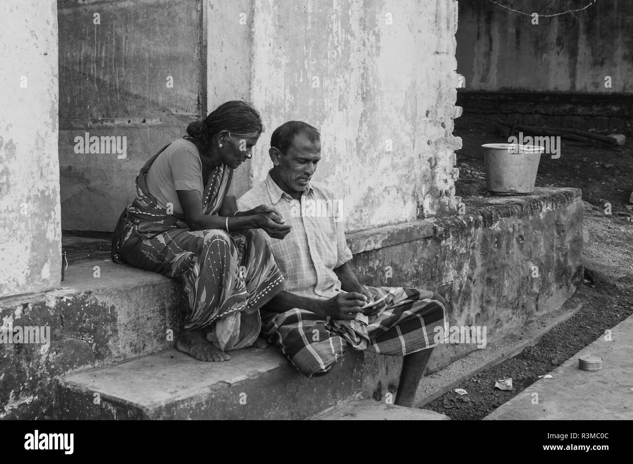 Indian senior couple sitting on the house exterior step Stock Photo