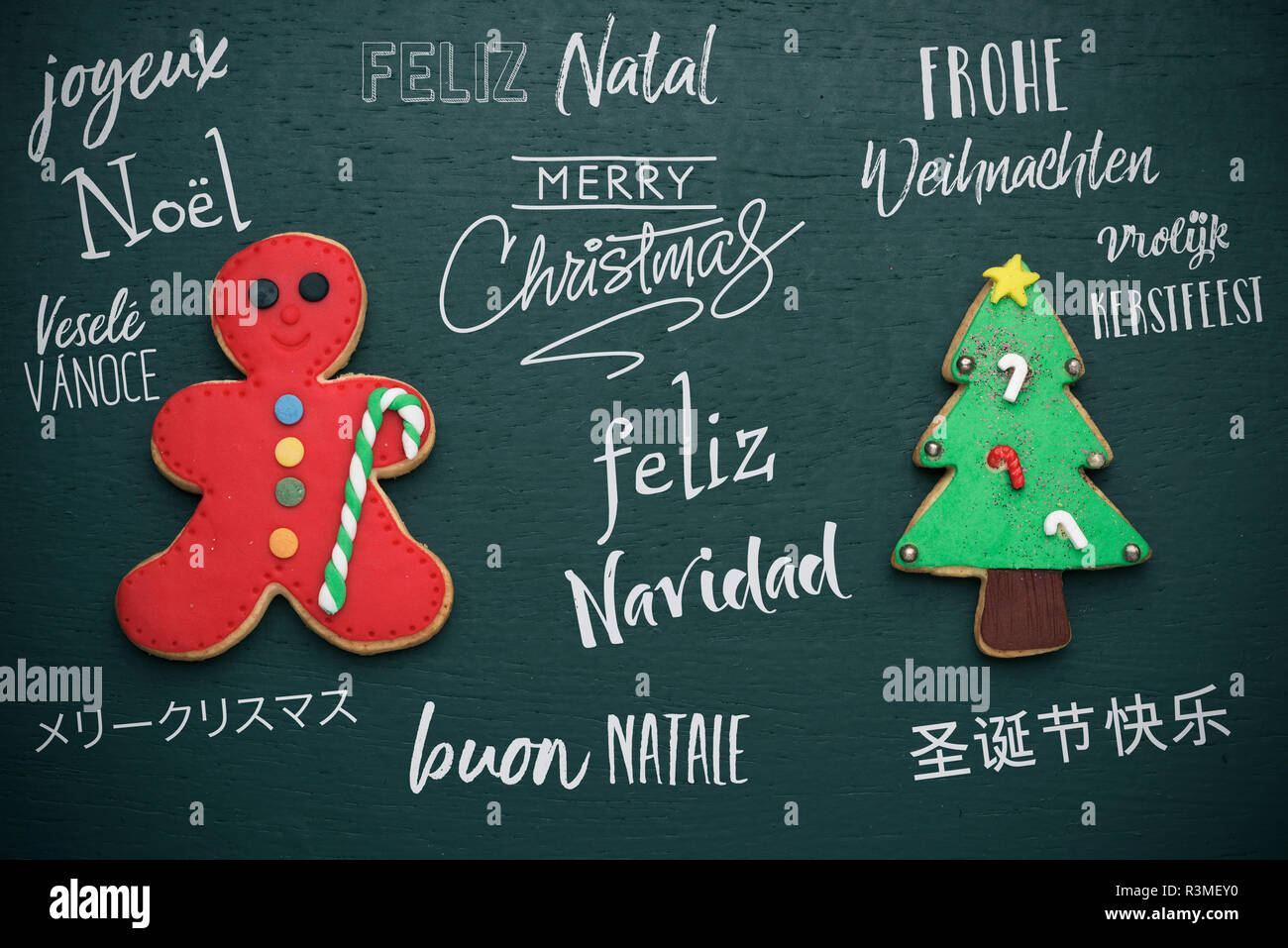 homemade cookies in the shape of a candy cane and a christmas tree, and the text merry christmas in different languages, such as german, czech, japane Stock Photo