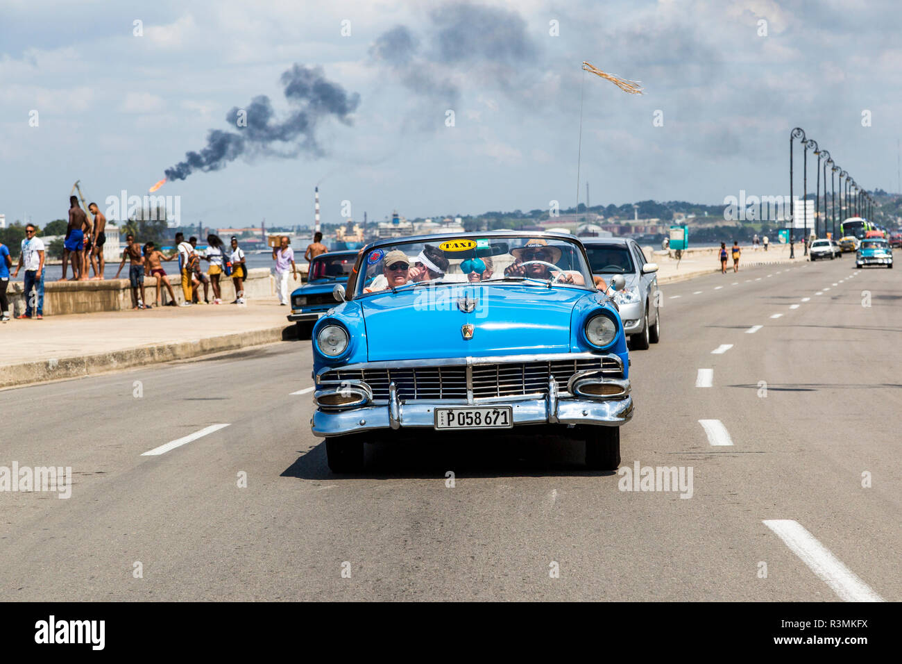 Tourists ride in a classic car along the Malecon waterfront in downtown