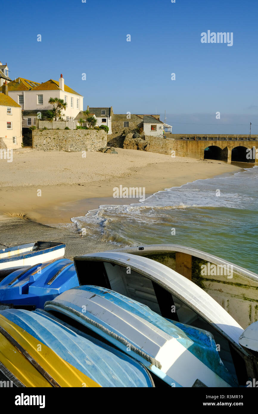 Small rowing boats stacked on the quayside in winter at St Ives Harbour in Cornwall Stock Photo