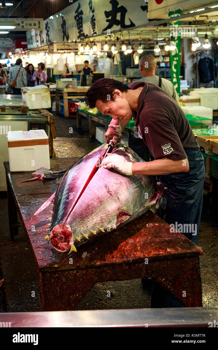 Tokyo, Japan. Fish monger fillets a large yellowfin tuna for sale at