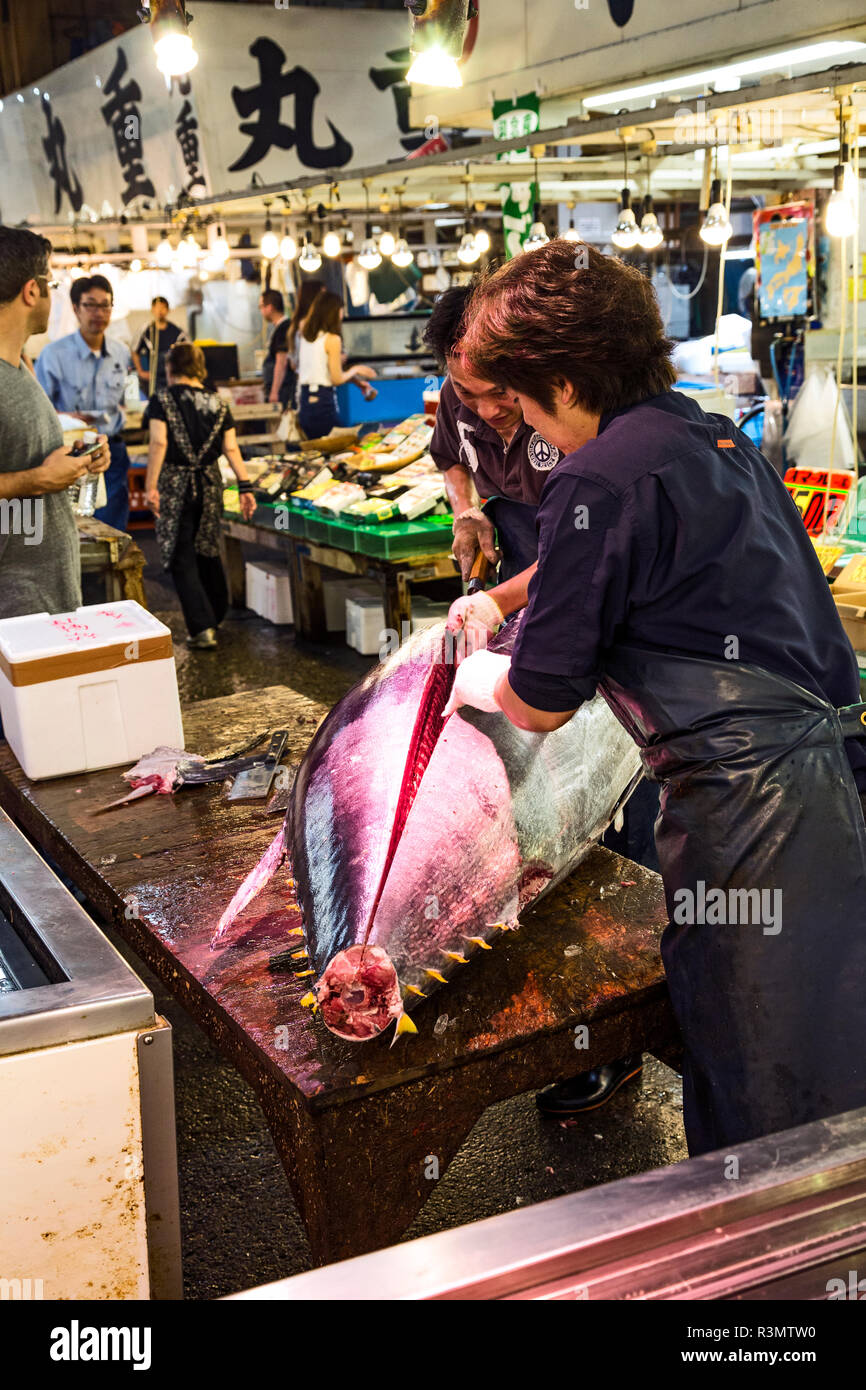 Tokyo, Japan. Fish monger fillets a large yellowfin tuna for sale at