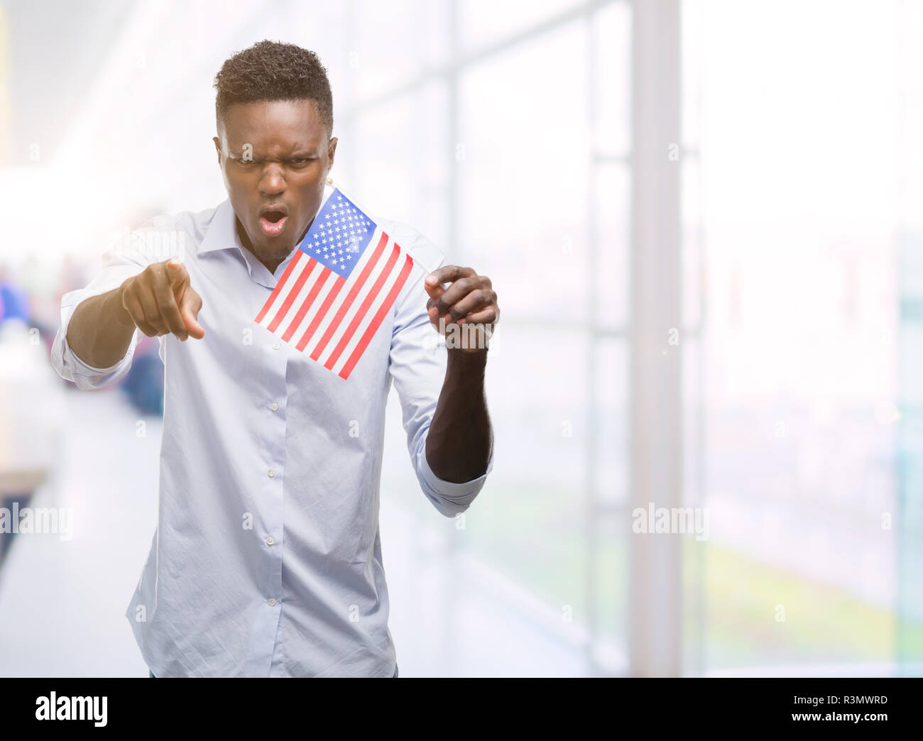 Young african american man holding USA flag pointing with finger to the ...