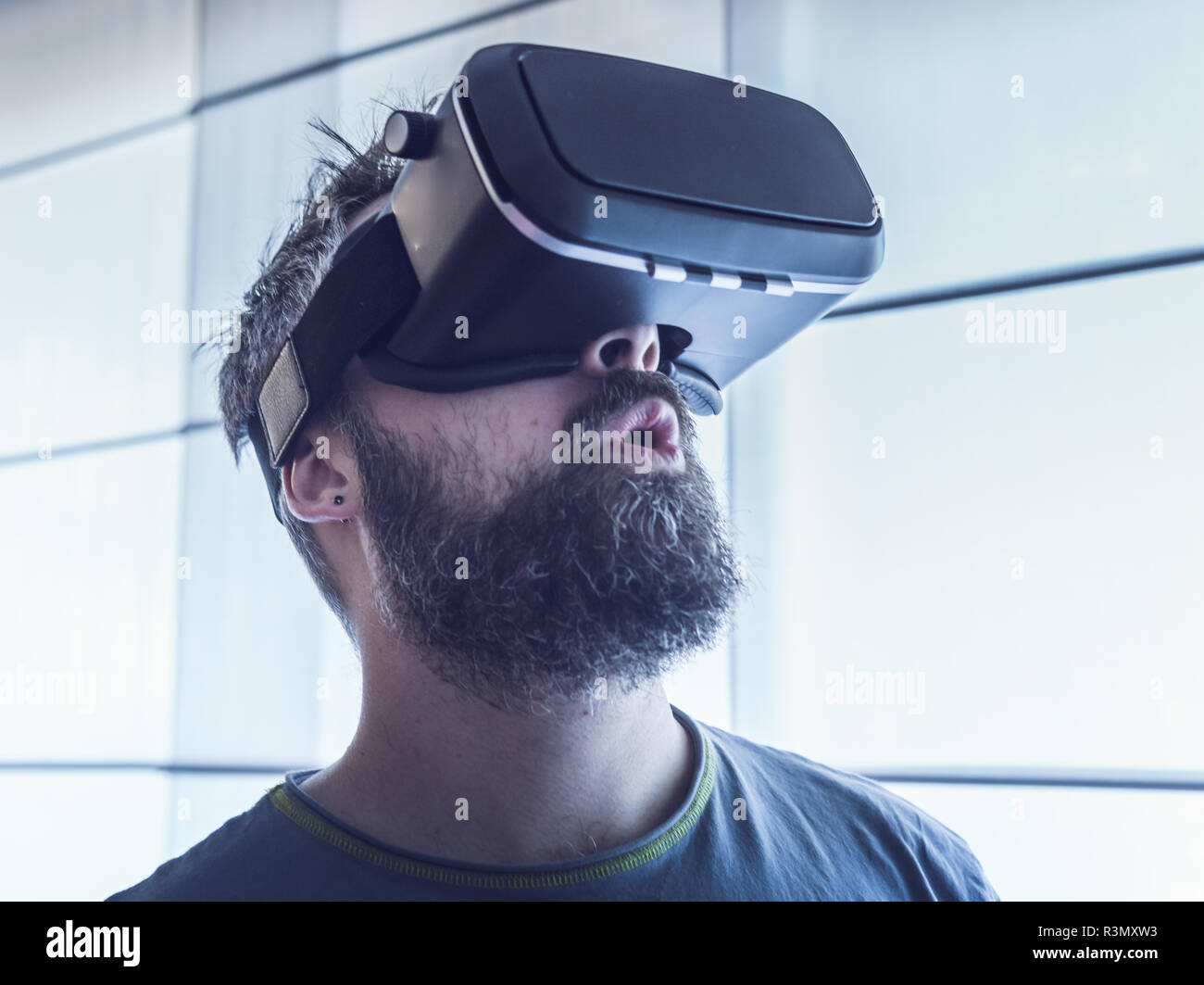 Portrait of young bearded man wearing virtual reality glasses in futuristic interior design. Expression of amazement on her face Stock Photo