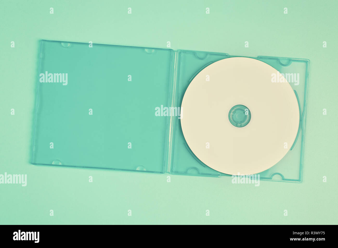 White cd in transparent case on pastel green background Stock Photo
