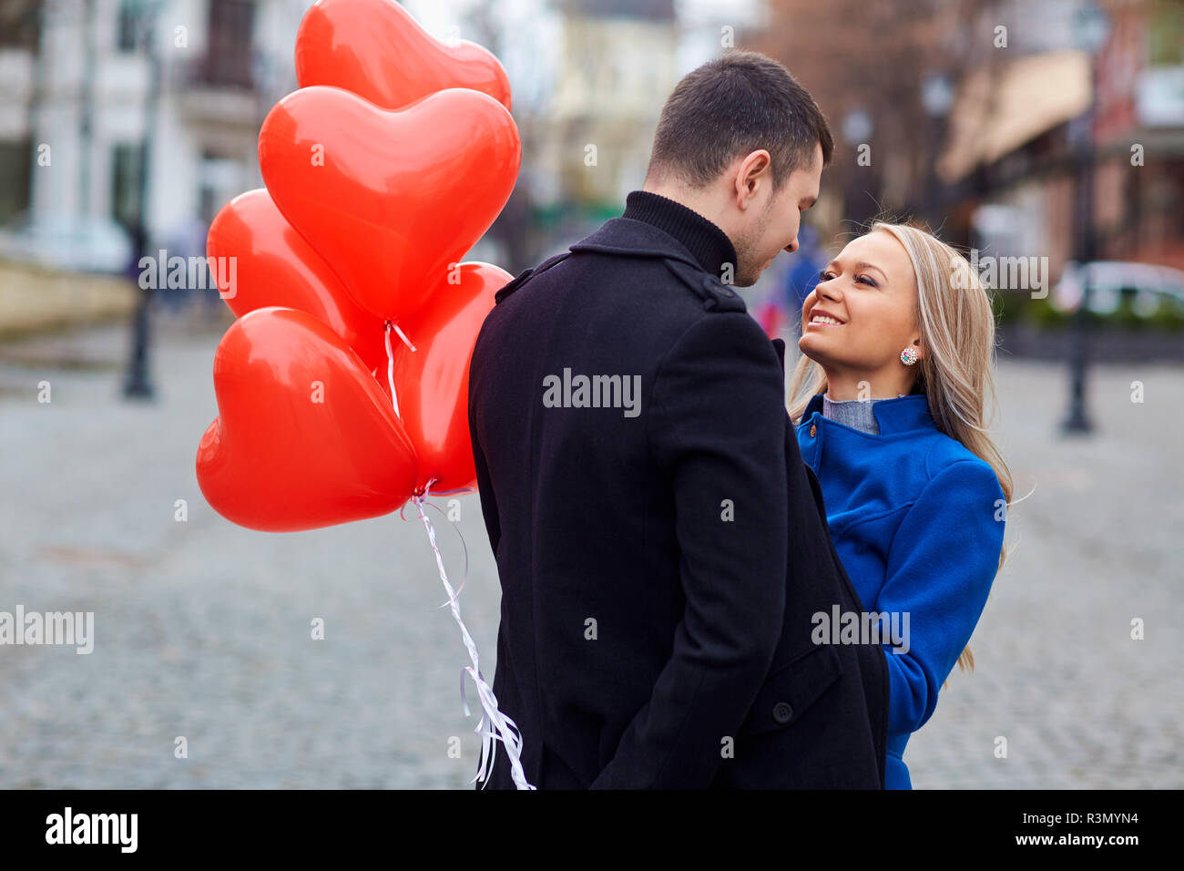 A loving couple in a coat with balloons hearts in hands Stock Photo - Alamy