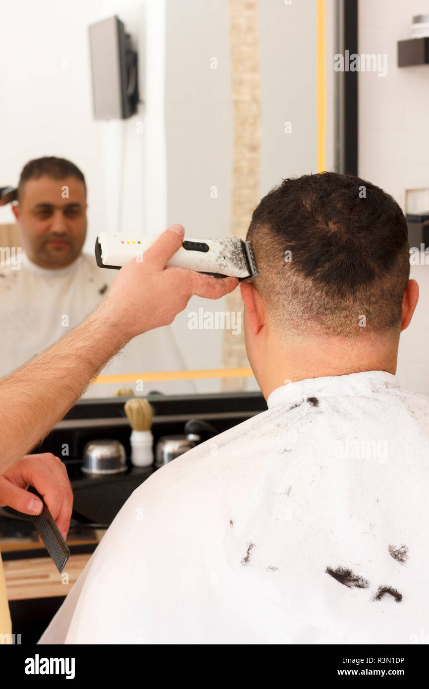 Back view of man getting short hair trimming at barber shop with a ...