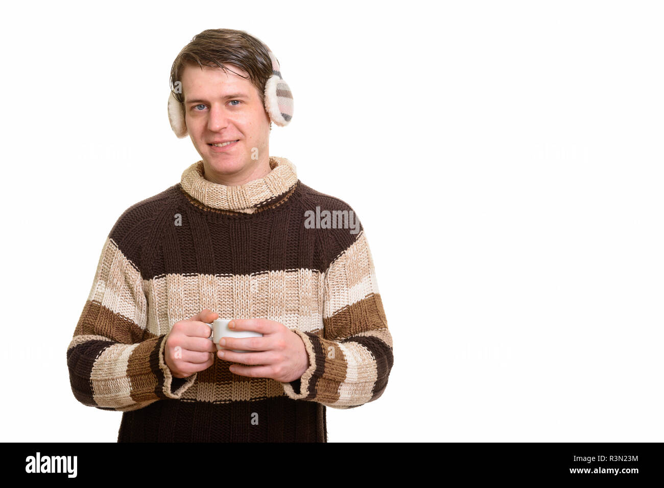 Happy handsome Caucasian man wearing winter earmuffs and holding Stock Photo