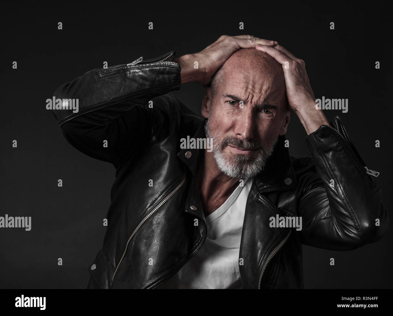 Creative studio portrait of actor and model Stefano Pasianot. He's wearing a white t-shirt and a leather jacket. Black background. Stock Photo