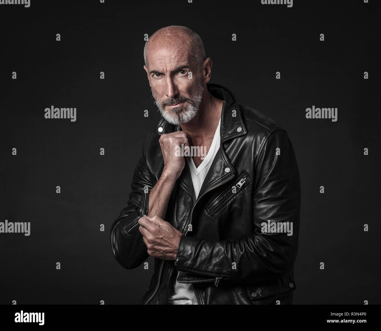 Creative studio portrait of actor and model Stefano Pasianot. He's wearing a white t-shirt and a leather jacket. Black background. Stock Photo