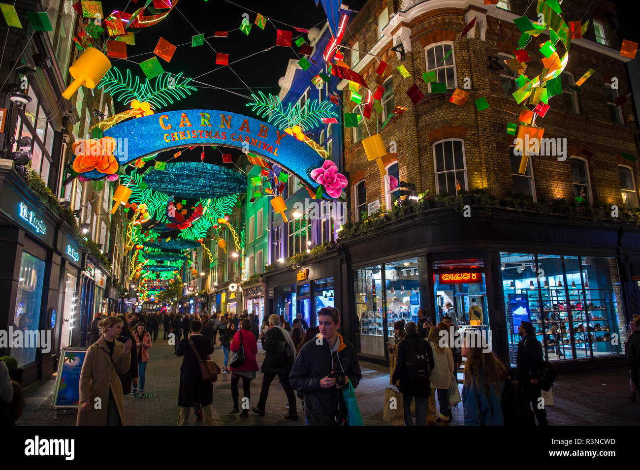 LONDON - CIRCA DECEMBER, 2017: Shoppers crowd the retail district of Carnaby Street, decorated for the holidays with a ‘Christmas Carnival’ theme. Stock Photo