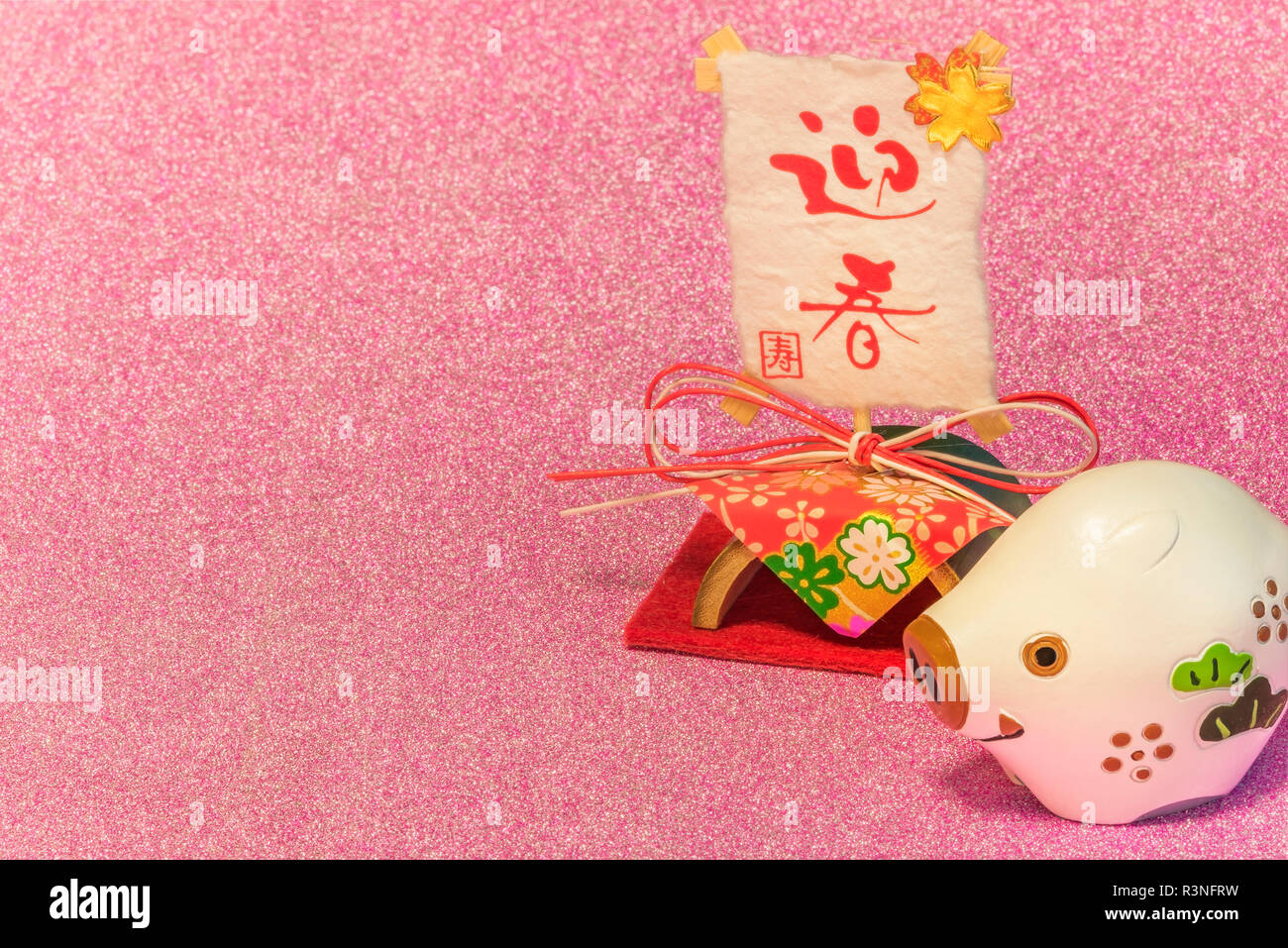 Glitter background for japanese New Year's Cards with cute animal figurine of boar or pig and rice paper with handwriting ideograms Geishun which mean Stock Photo