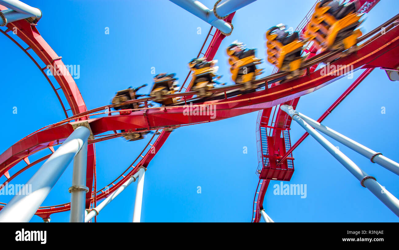 yellow roller coaster with people inside move fast, high speed, in roller rail in amusement park for fun with clear blue sky Stock Photo