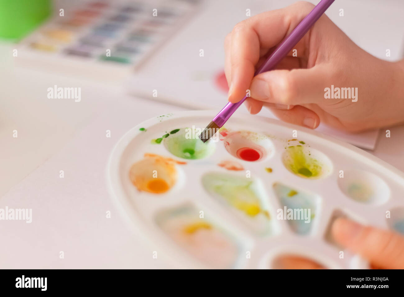 Person using watercolor paints with a brush. Shallow depth of field. Close up. Stock Photo