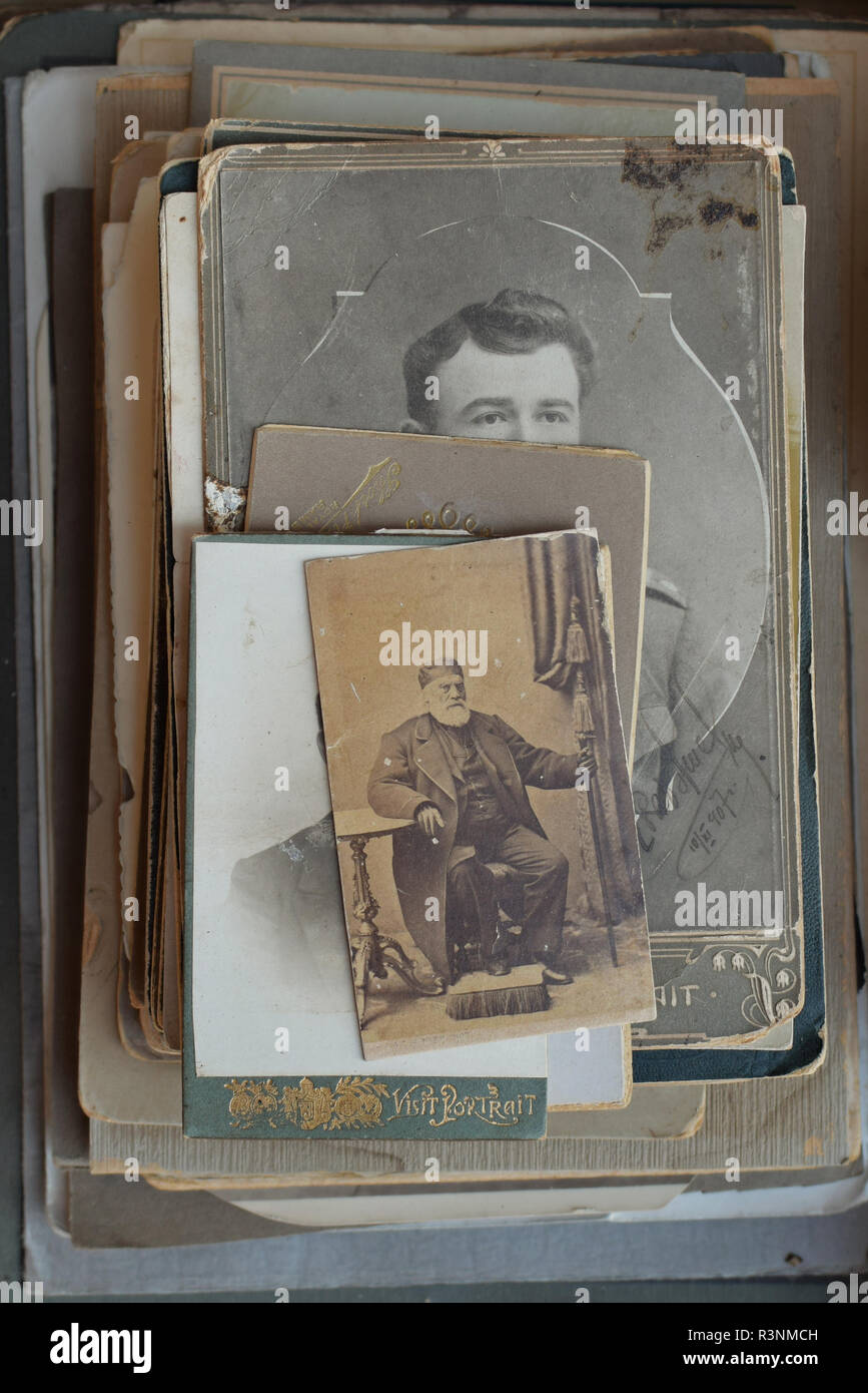 ATHENS, GREECE - SEPTEMBER 14, 2018: Vintage photo of bearded man with cane and footstool. Pile of old photographs and postcards at antiques store. Stock Photo