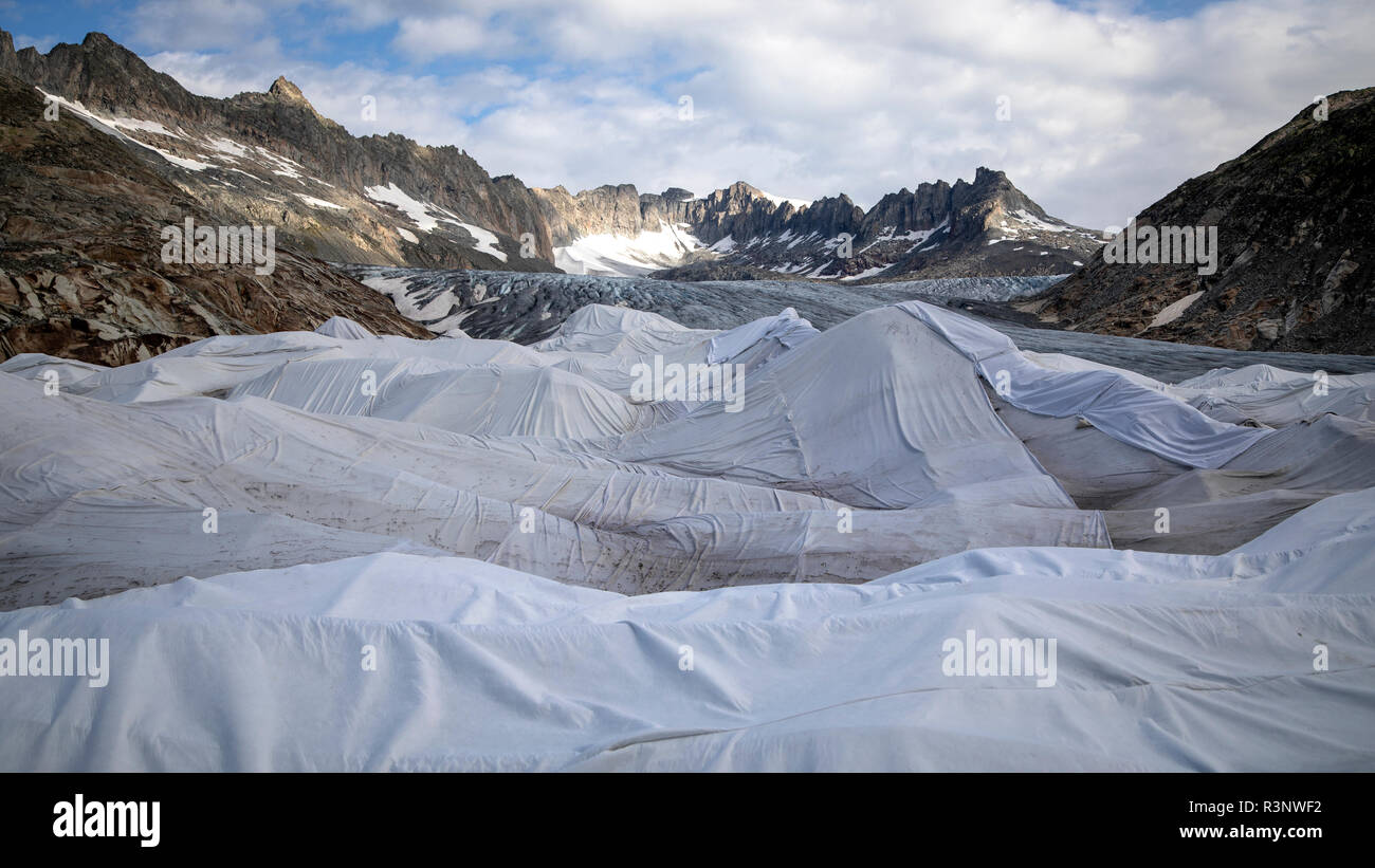 Climate | Albedo | Rhone: Huge fleece blankets cover parts of the Rhone Glacier in Switzerland in an attempt to stall the inevitable melting of the snow and ice. After a winter with record amounts of snow, most of it was gone when this image was taken on July 14th 2018, exposing the darker ice. While snow is a brilliant reflector of the energy from the sun, the darker ice absorbs the energy instead, accelerating the melting of the glacier. The color and darkness of glacier ice vary all over the world, depending on build-up of pollution, age of the ice, particles picked up by the ice and by mic Stock Photo