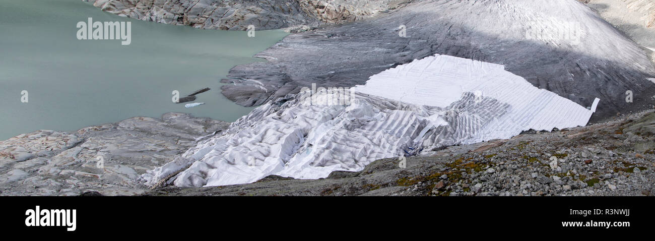 Climate | Albedo | Rhone: Huge fleece blankets cover parts of the Rhone Glacier in Switzerland in an attempt to stall the inevitable melting of the snow and ice. After a winter with record amounts of snow, most of it was gone when this image was taken on July 14th 2018, exposing the darker ice. While snow is a brilliant reflector of the energy from the sun, the darker ice absorbs the energy instead, accelerating the melting of the glacier. The color and darkness of glacier ice vary all over the world, depending on build-up of pollution, age of the ice, particles picked up by the ice and by mic Stock Photo