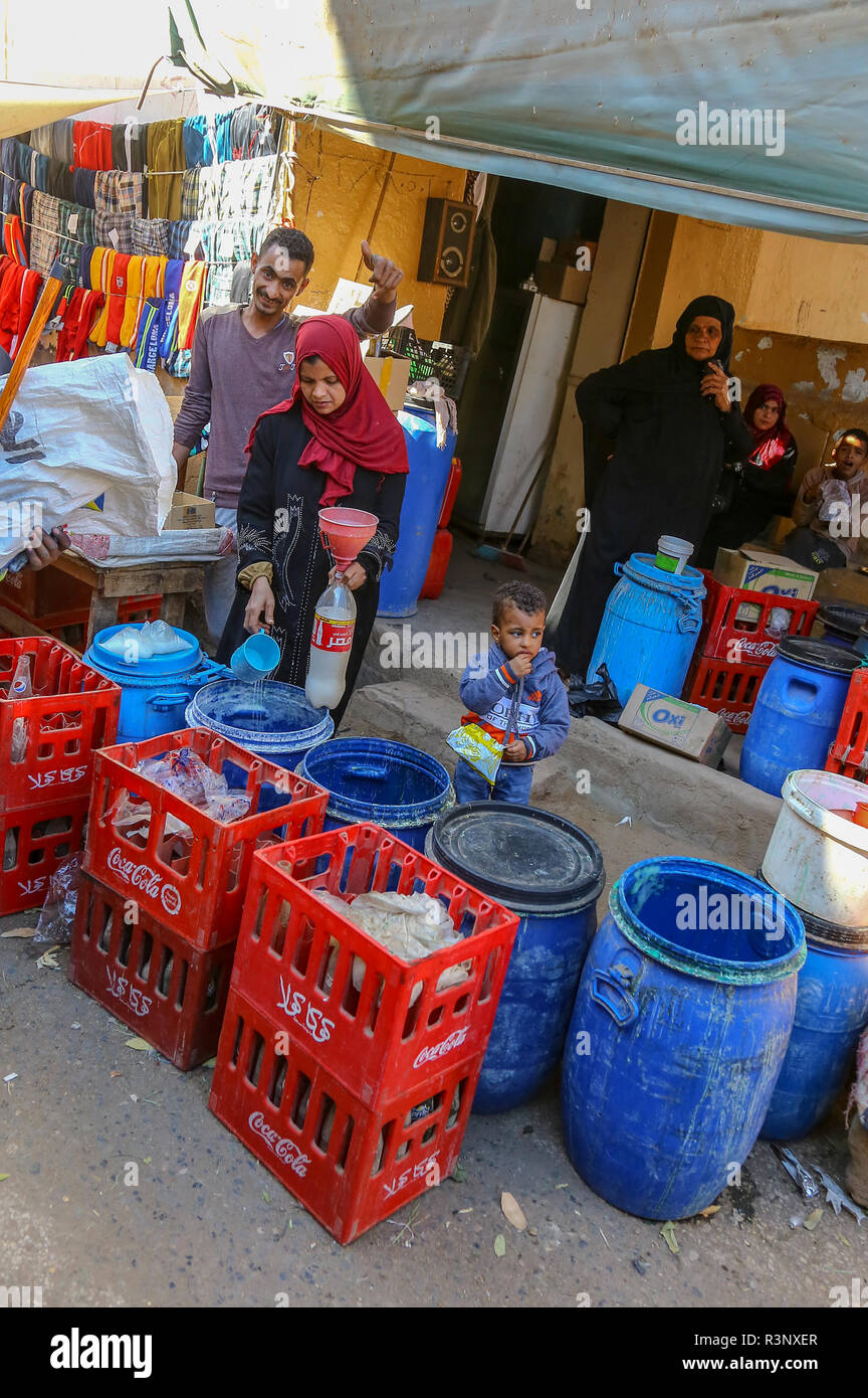 A woman ladling or pouring milk into a bottle with a man giving the thumbs up sign at a local market at Edfu, Upper Egypt, North Africa Stock Photo