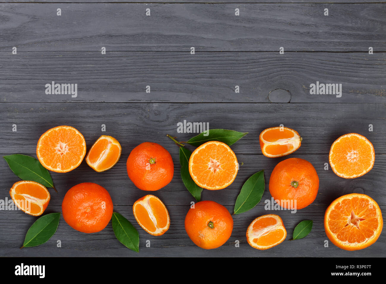 Premium Photo  Mandarins scattered across the table from a blue pouch. fresh  mandarin oranges fruit or tangerines on gray table. flat lay and copy space