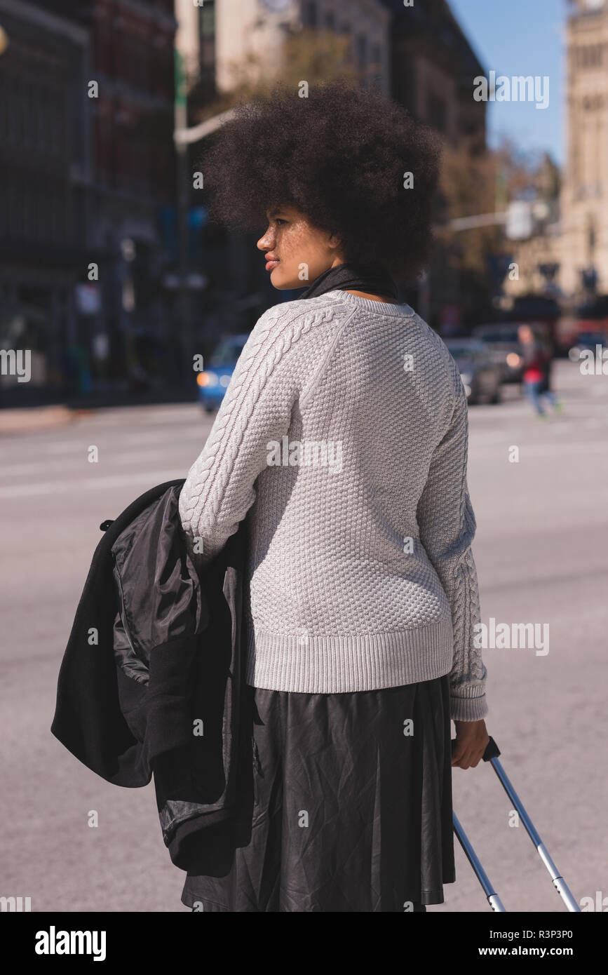 Woman with luggage bag walking in city Stock Photo
