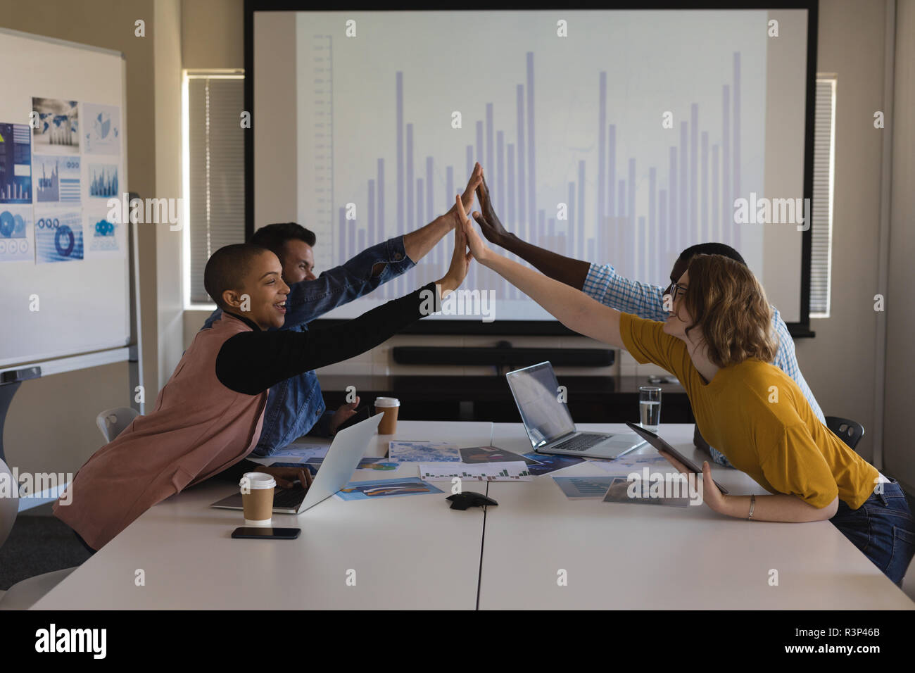 Executives giving hi five to each other in conference room Stock Photo