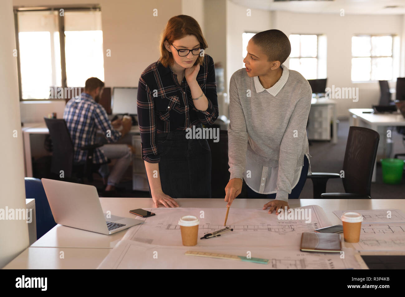 Business executives discussing over blueprint on table Stock Photo
