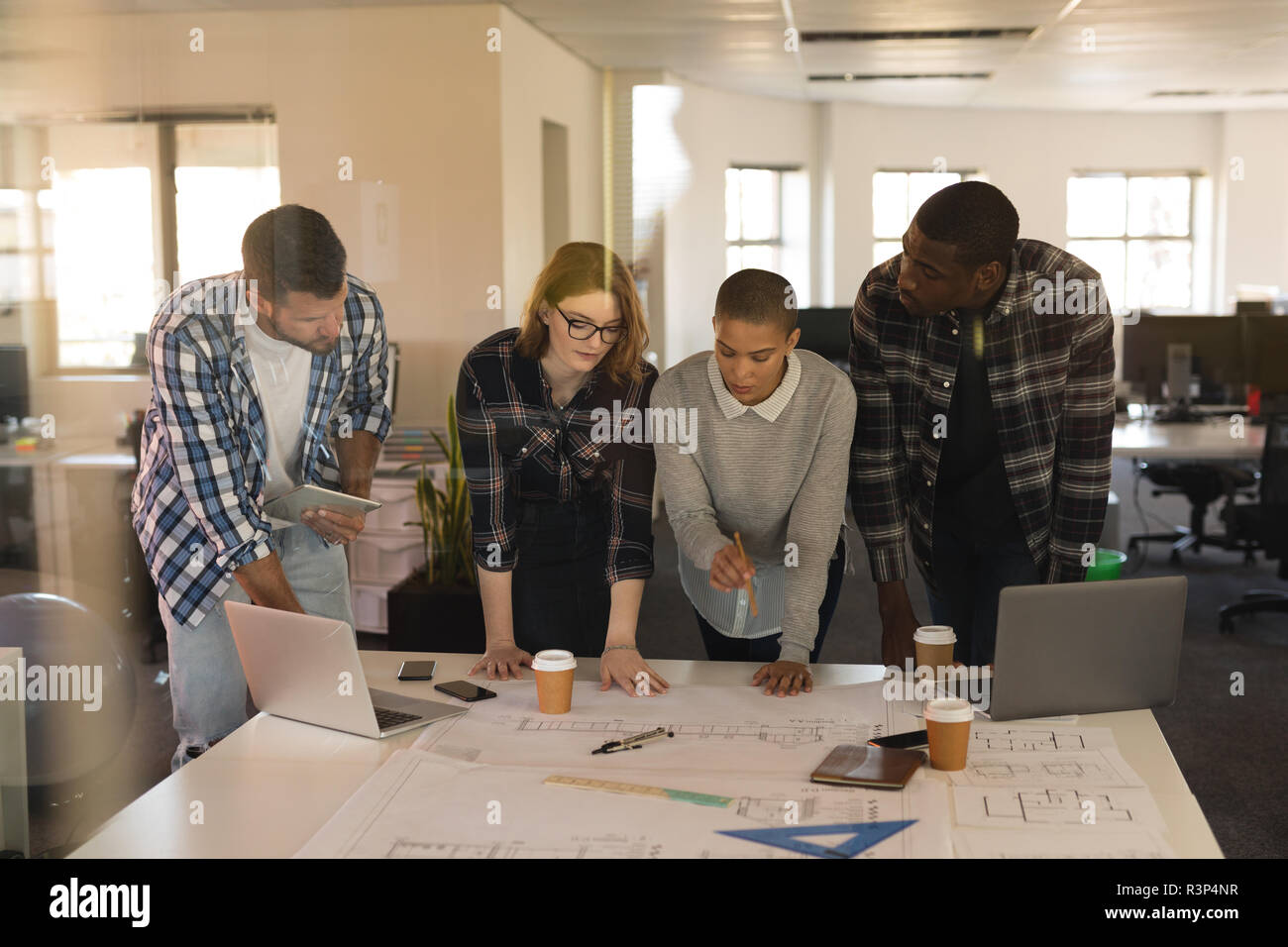 Business executives discussing over blueprint on table Stock Photo
