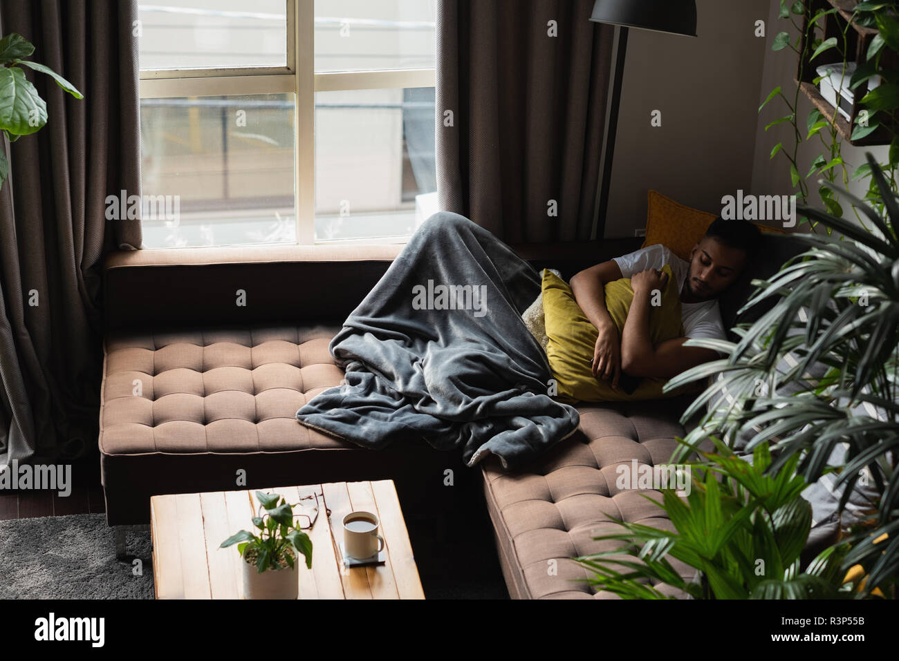 Man sleeping on sofa in living room Stock Photo