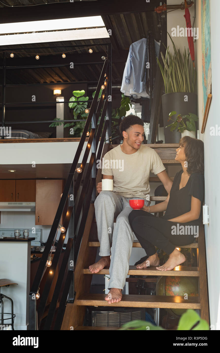 Couple interacting with each other while having coffee in stairs Stock Photo