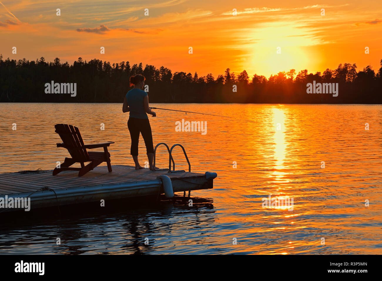 Canada, Manitoba, Whiteshell Provincial Park. Woman fishing off dock on