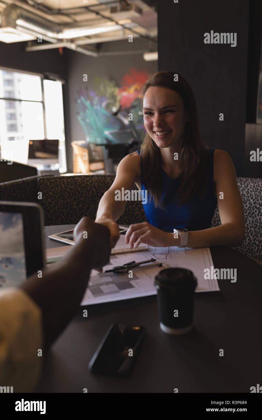 Business colleagues shaking hands in cafeteria Stock Photo
