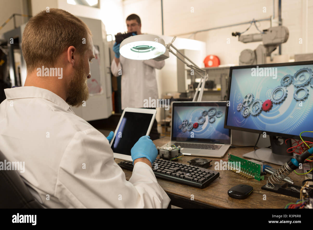 Robotics engineer using digital tablet at desk Stock Photo