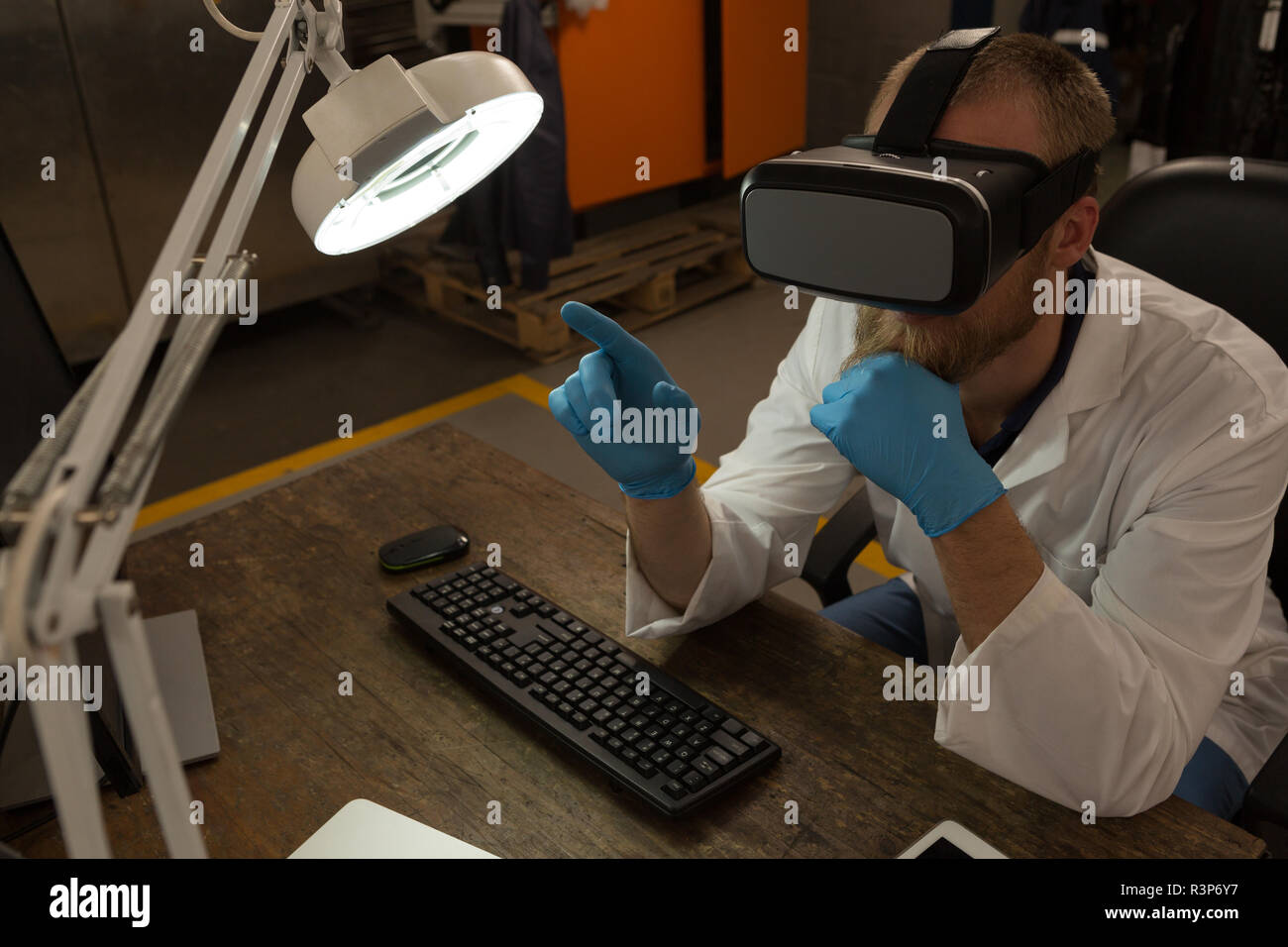 Robotics engineer using virtual reality headset at desk Stock Photo