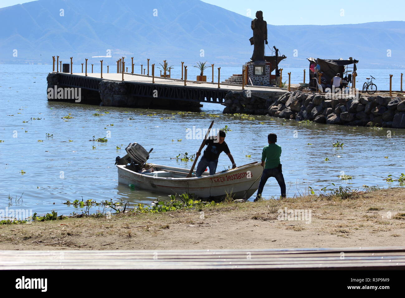 Lago de Chapala,foto tomada a la orilla del lago en donde aparecen 2 pescadores en primer plano  preparando su bote para salir a la pesca del dia Stock Photo