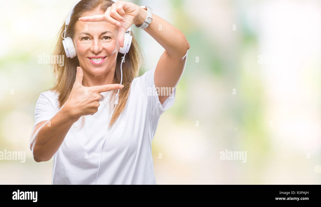 Middle age hispanic woman listening to music wearing headphones over ...