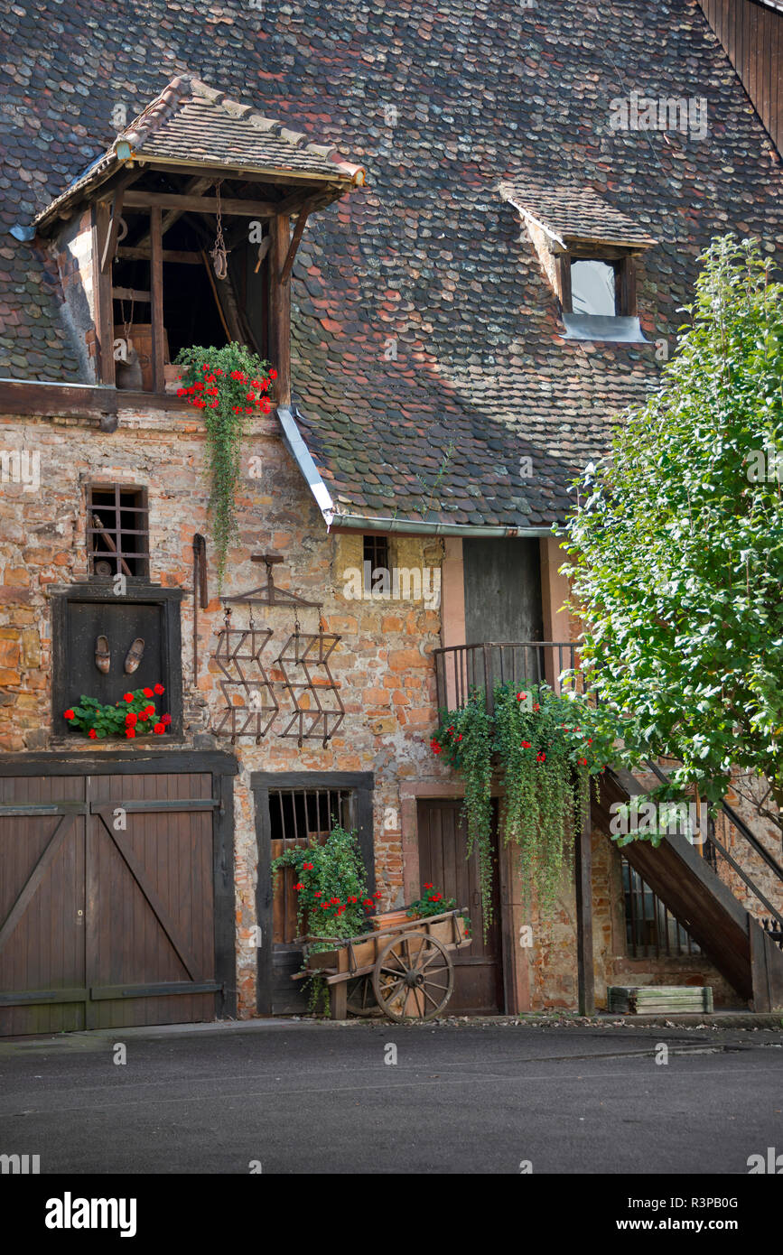 France, Alsace, Colmar. Rustic brick and wood building with a cart. Stock Photo