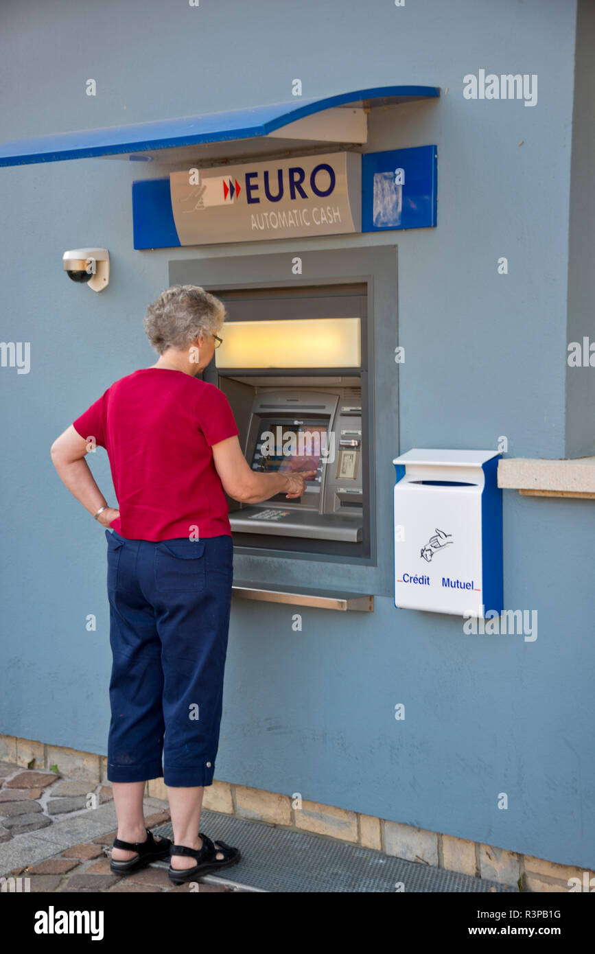 France, Alsace, Colmar. A woman withdraws Euros from an ATM in Colmar. (MR) Stock Photo