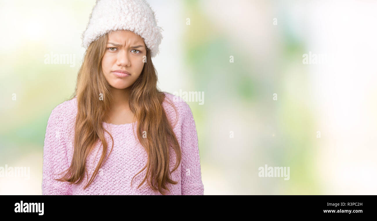 Young beautiful brunette woman wearing sweater and winter hat over isolated background skeptic and nervous, frowning upset because of problem. Negativ Stock Photo